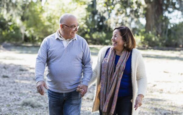 Senior Hispanic couple walking in park holding hands